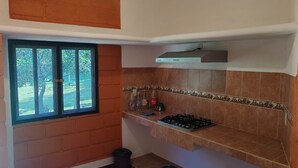 A compact kitchen with a gas stove, a window, and a trash bin. - Perfect 1-bedroom house in enchanting Tepoztlán for your getaway (Tepoztlán)