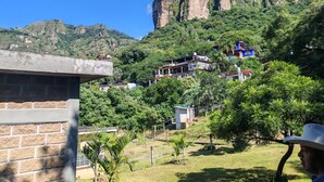A hillside with buildings, including a prominent cliff and a blue-roofed structure. - Perfect 1-bedroom house in enchanting Tepoztlán for your getaway (Tepoztlán)