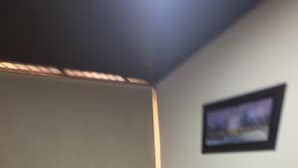 Une chambre avec deux lits simples et un lit plus grand, tous dotés de linge de lit blanc et de touches de couleur grise. La chambre a un sol carrelé et un tableau encadré au mur.