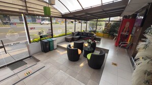 Un espace extérieur abrité, aménagé avec des meubles en osier et un réfrigérateur Coca-Cola.
