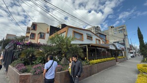 Un hôtel doté d’une façade moderne, d’un espace extérieur couvert aménagé en coin salon et offrant une vue sur la rue.