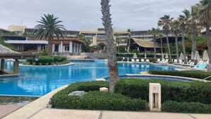 Una gran piscina al aire libre rodeada de palmeras y sillas de descanso.