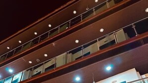 Un hotel de varios pisos con un diseño moderno, con balcones en cada planta, ventanas amplias y una entrada destacada.