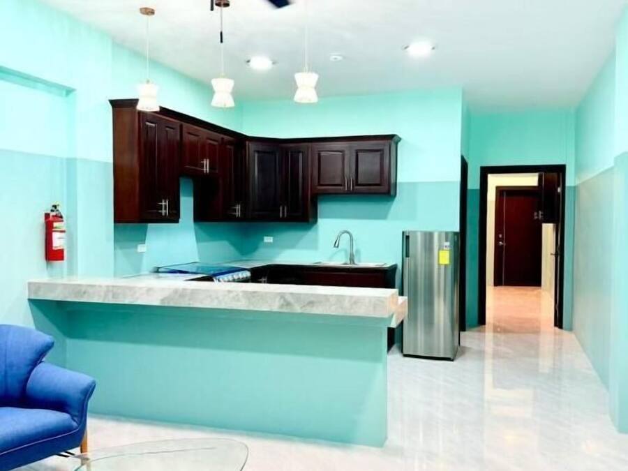 Una cocina moderna con armarios oscuros, una encimera de mármol, una mesa de centro de vidrio y un ventilador de techo.