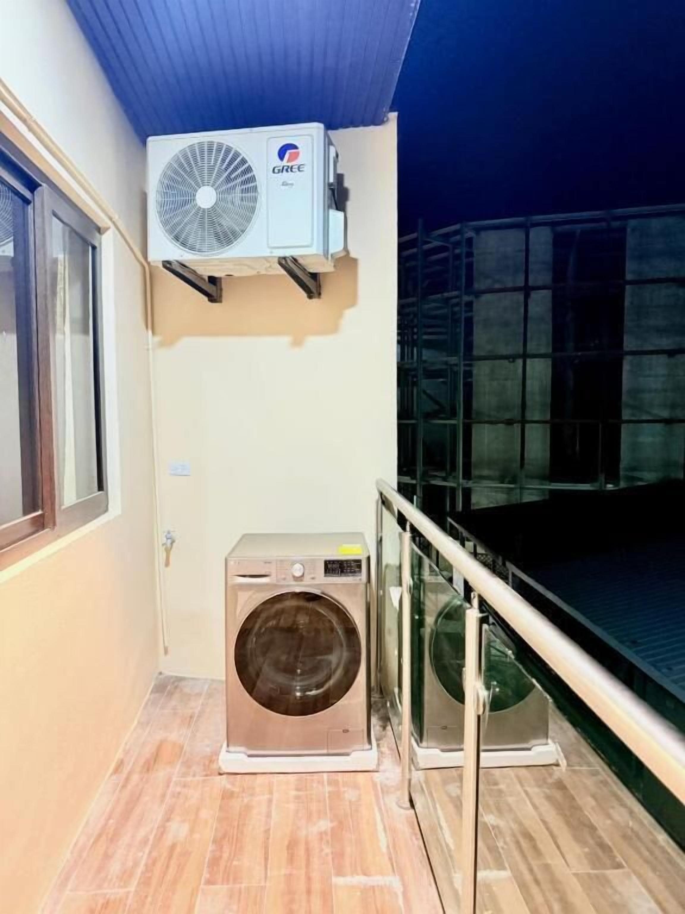 A balcony with a washing machine and an air conditioning unit.