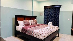 Una cama bien hecha con una colcha estampada y almohadas, un cabecero de madera oscura y un adorno en la pared.