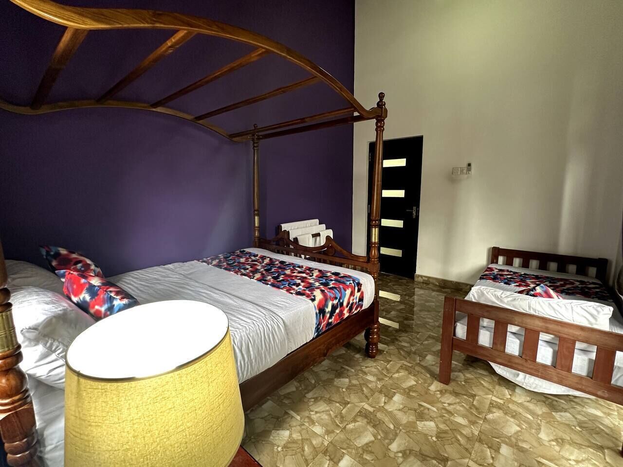 Een kamer met een hemelbed, een nachtkastje en een lamp.
