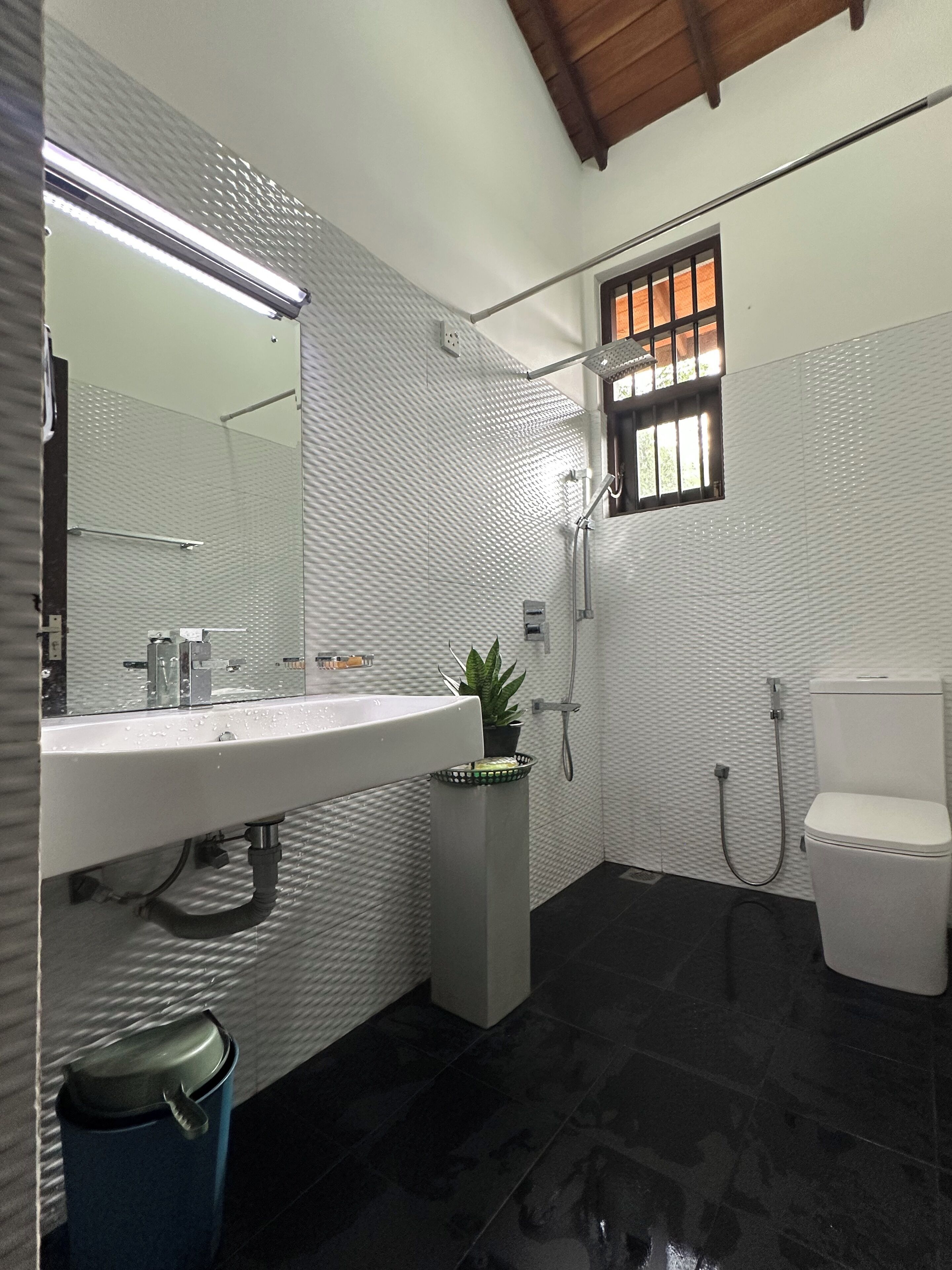 Een moderne badkamer met een wit wastafelmeubel, toilet en douche.