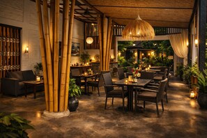 A restaurant with bamboo columns, wicker furniture, and warm lighting. - Kampoeng Villa Ubud (Ubud)