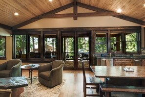 A spacious interior with a high ceiling, large windows, and a rustic wooden dining area.