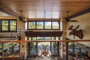 A spacious interior with a high ceiling, large windows, and a mounted moose head.