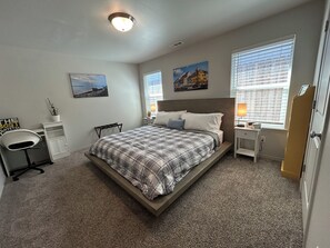 A bedroom with a bed, bedside tables, a chair, and artwork on the walls. - Columbia River View near Toyota Center, large fenced yard in Kennewick (Kennewick)