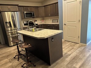 A kitchen with a central island, stainless steel appliances, and dark cabinetry. - Columbia River View near Toyota Center, large fenced yard in Kennewick (Kennewick)