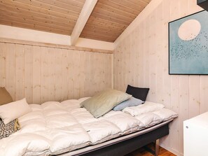 Un dormitorio con cama, techo de madera y una obra de arte colgada en la pared.