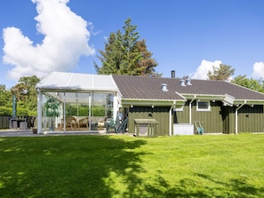 A house with a glass-enclosed patio, a green lawn, and a chimney. - 4 Star Holiday Home in Hals (Hals)