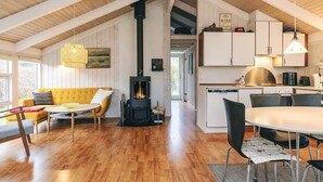 Ein gemütlicher Loftraum mit Holzbalkendecke, Kamin, Essbereich und Küche mit weißen Schränken.