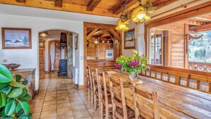 Ein Holzkamin mit einem langen Esstisch, Stühlen und einer hängenden Leuchte.