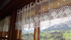 Ein Fenster mit Blick auf eine grüne Landschaft und Berge.