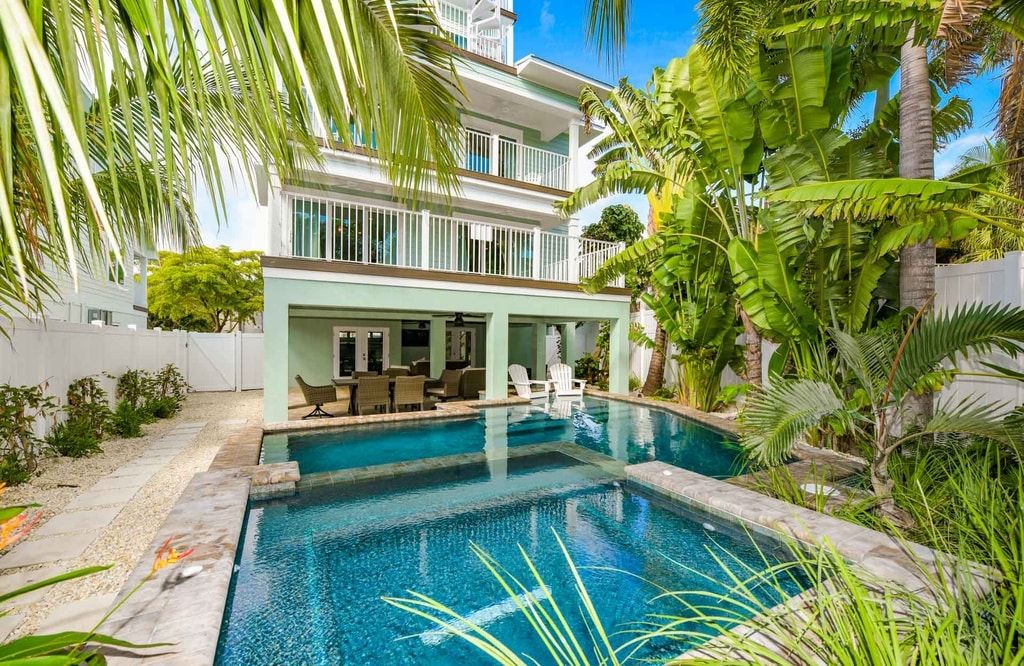 Un bâtiment à deux étages doté d’une piscine entour ée de plantes tropicales.