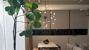A modern kitchen with a dining area, a large potted plant, a hanging light fixture, and a patterned rug. - Luxury 2BR Downtown Apartment – Close to Mercedes-Benz Stadium – World Cup 2026 (Atlanta)