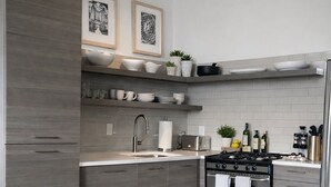 A modern kitchen with grey cabinetry, a stove, and a sink. There is a cowhide rug on the floor. - Luxury 2BR Downtown Apartment – Close to Mercedes-Benz Stadium – World Cup 2026 (Atlanta)