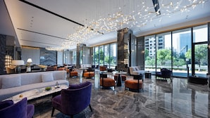 A modern hotel lobby with a marble floor, plush seating, and large windows offering city views. - Mehood Elegant Hotel Shaoxing Shangyu (Shaoxing)
