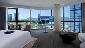 A hotel room with a large TV, a bed, a sofa, and a view of the cityscape. - Mehood Elegant Hotel Shaoxing Shangyu (Shaoxing)