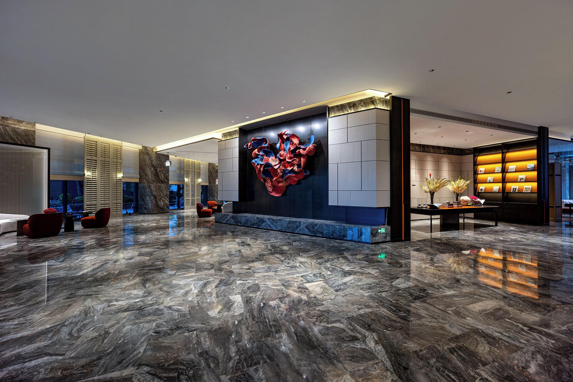 A spacious lobby with a large abstract art piece, a reception desk, and seating areas.