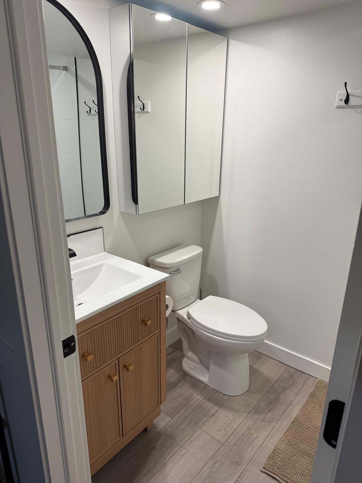 Ein Badezimmer mit Waschbecken, Holzwaschtisch, Toilette und Spiegel.