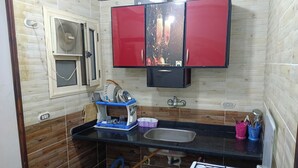 Una cocina compacta con estufa a gas, un lavamanos y paneles de madera.