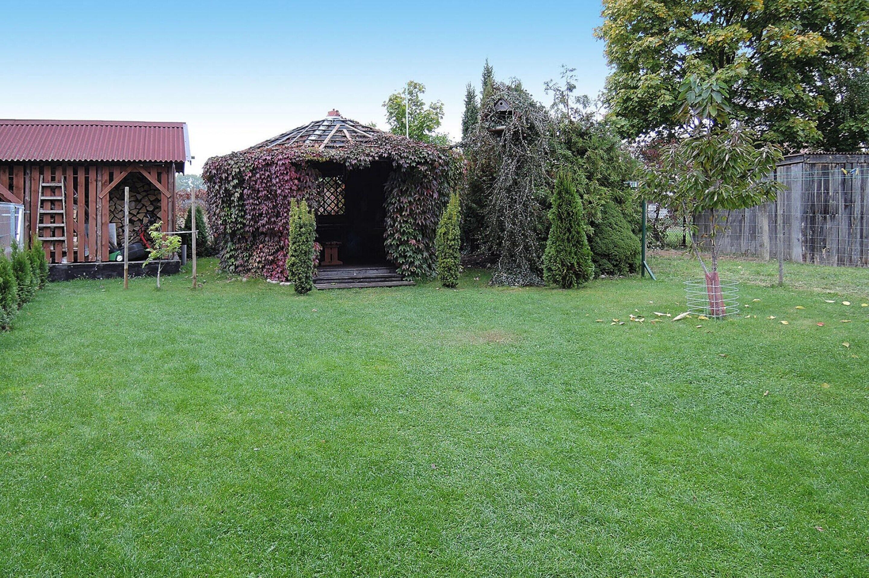 A garden with a gazebo, a wooden shed, and a fenced area.