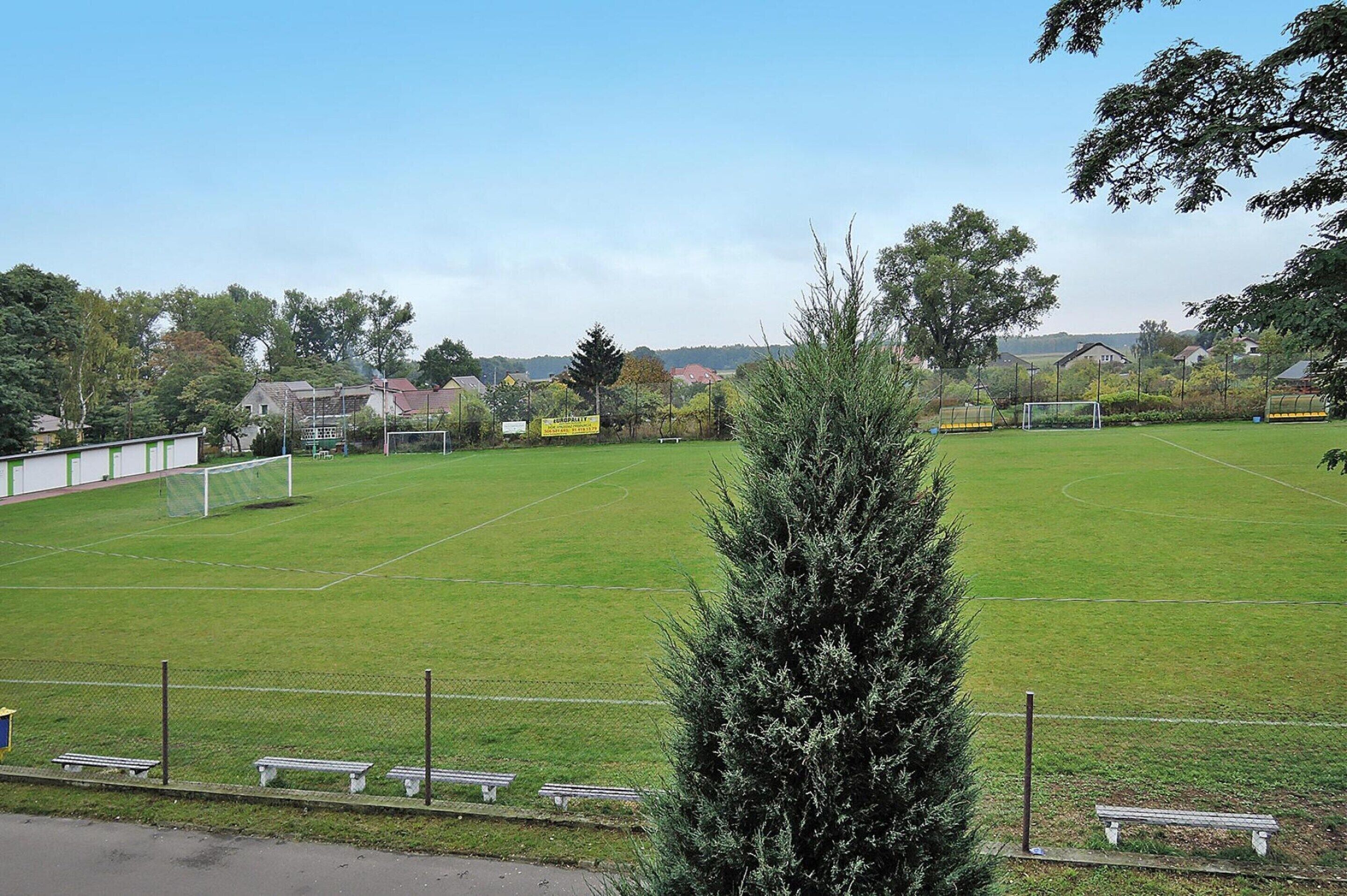 Un terrain de football avec des poteaux de but, des bancs et une clôture.