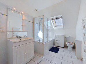 Un baño moderno con ducha de vidrio, inodoro y lavamanos con espejo.
