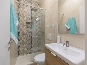 A bathroom with a shower, toilet, sink, and a mirror. - Two-room apartment near beach and town center (Procchio)