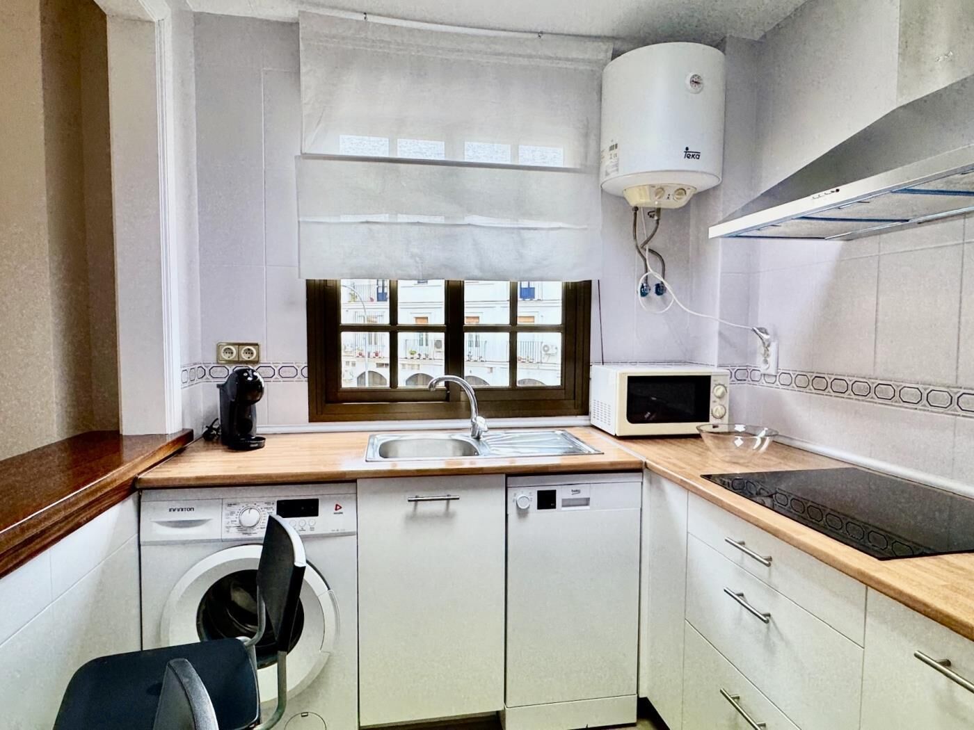 A compact kitchen with a built-in washing machine, a microwave, and a sink.