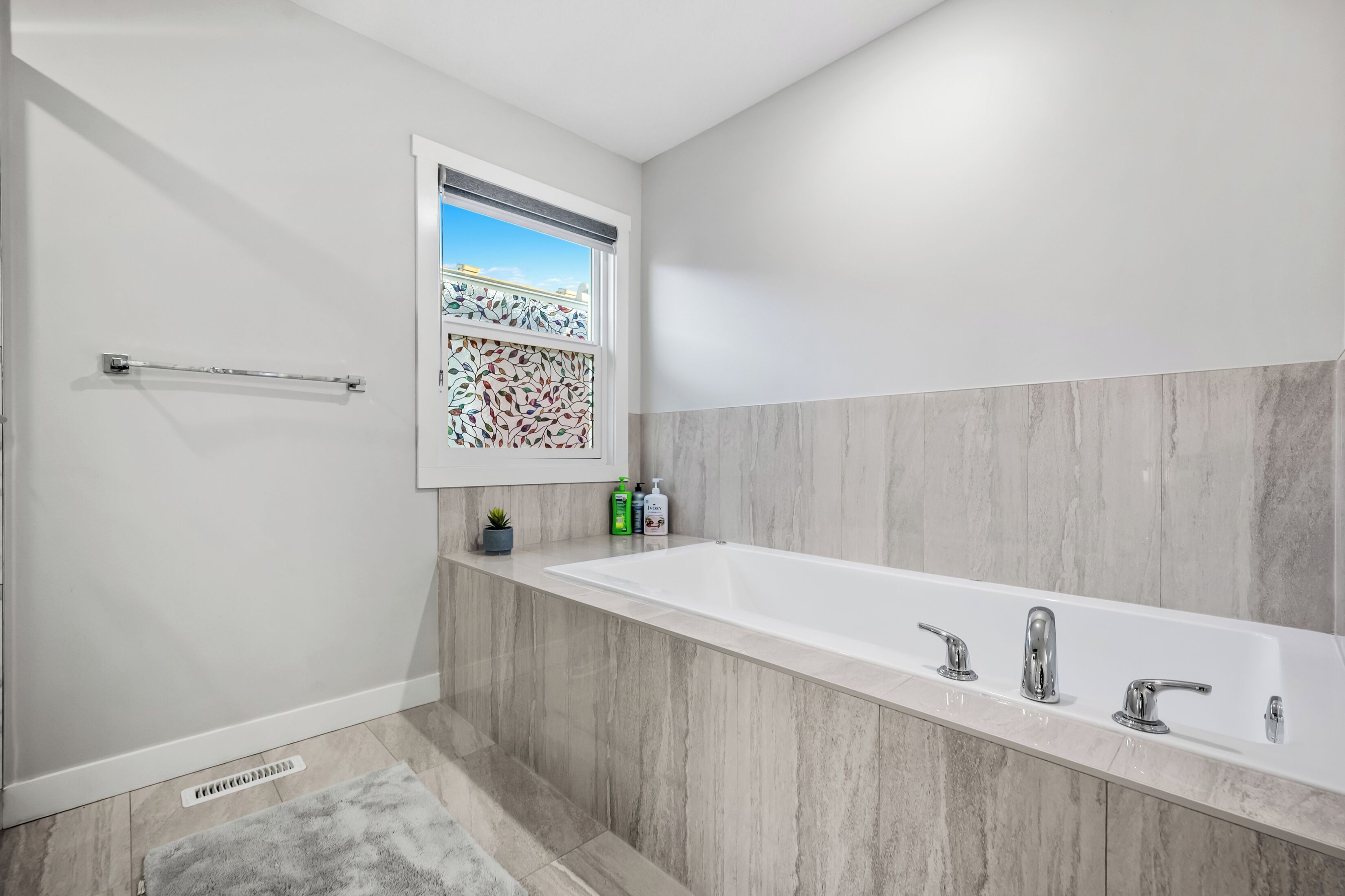 Une salle de bain moderne avec une grande baignoire, un porte-serviettes, une fenêtre donnant sur un beau paysage et une petite plante.