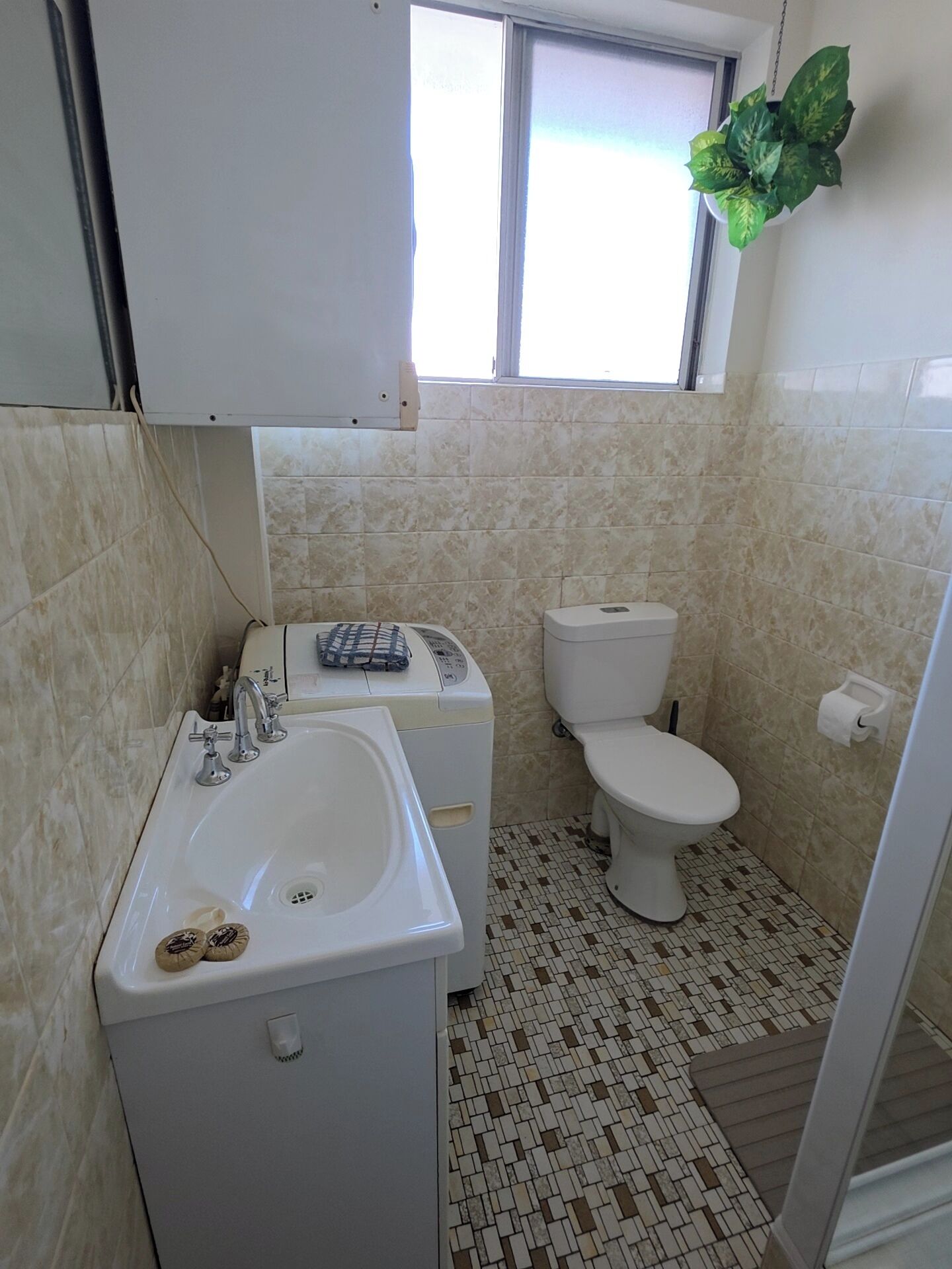 Ein kleines Badezimmer mit Waschbecken, Toilette und Fenster.