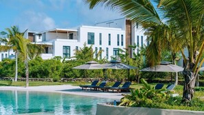 A modern resort with a swimming pool, lounge chairs, and palm trees. - Tropical Private Garden Oasis • Soul Paje • Lagoon Pool • Walk to Beach (Paje)