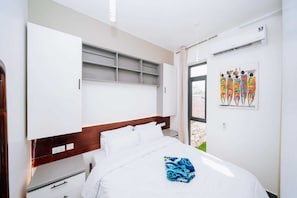 Ein Hotelzimmer mit Bett, Kleiderschrank, Fenster und Klimaanlage.