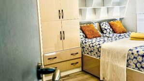 Een slaapkamer met een grote kast, een bed met behang en een zacht vloerkleed.