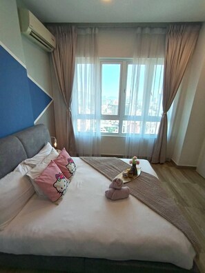 A hotel room with a bed, a blue accent wall, a window with curtains, and a view of the city. - OCTAGON PREMIUM IPOH l TOWN CENTER l by Grab A Stay l 6-8PAX (Ipoh)