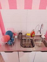Una cocina con un lavamanos, escurreplatos y diversos utensilios de cocina.