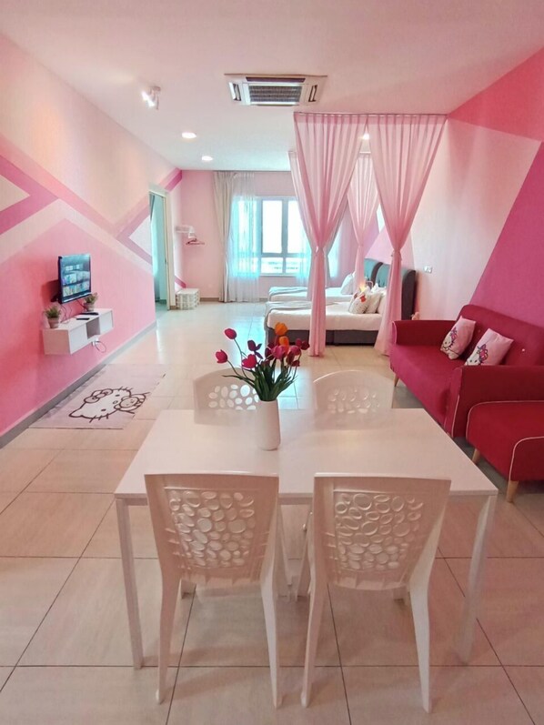 A modern hotel room with a pink and white color scheme, a dining area with a white table and chairs, a red sofa, and a bed with a canopy. - OCTAGON PREMIUM IPOH l TOWN CENTER l by Grab A Stay l 6-8PAX (Ipoh)