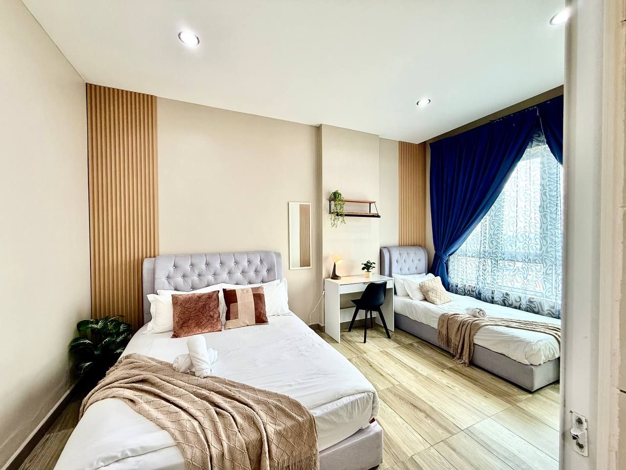 A hotel room with a large bed, a desk, and a window with curtains.