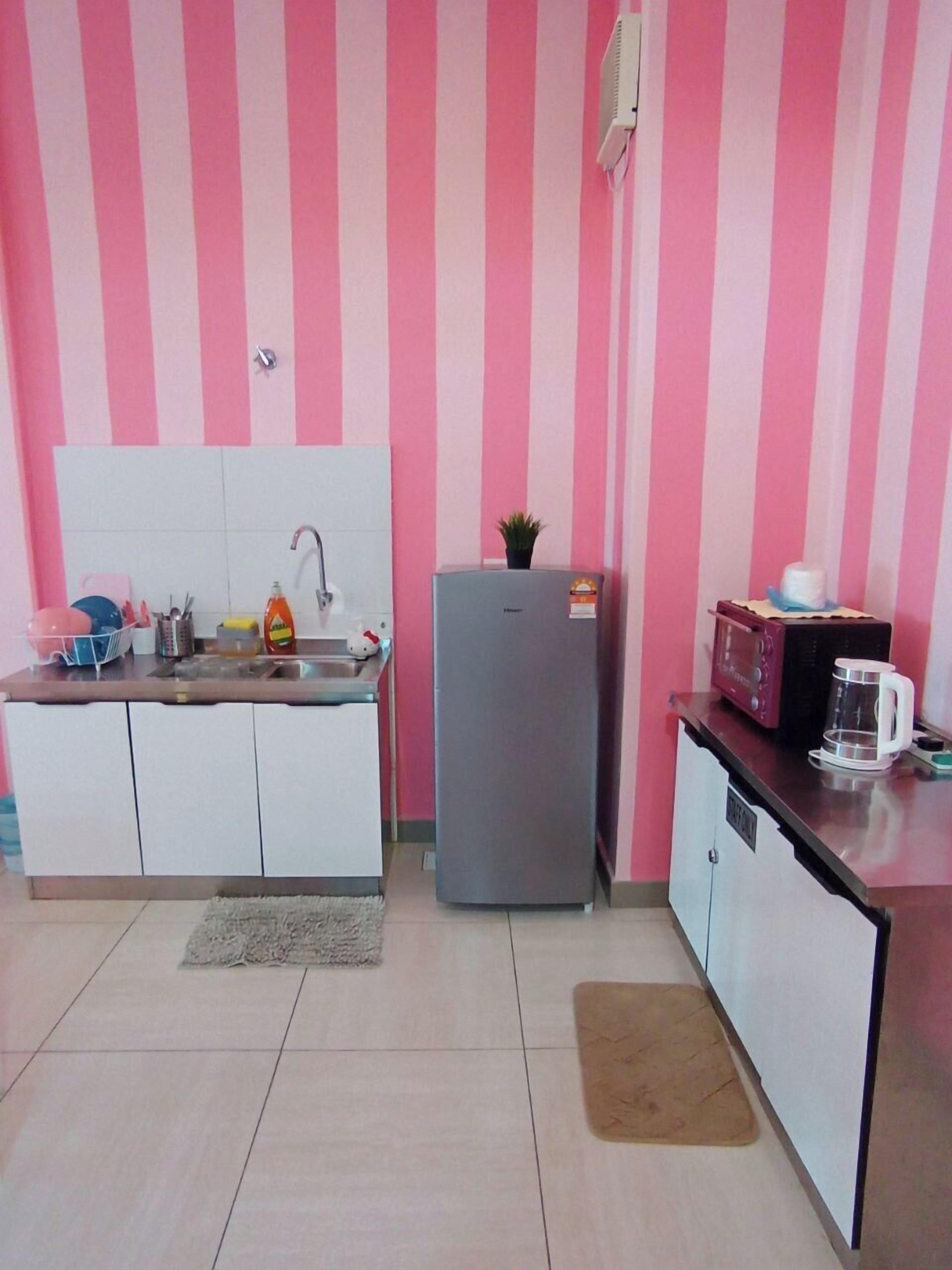 A compact kitchen with white cabinets, a grey refrigerator, a microwave, and a coffee maker on the counter.