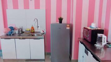 A compact kitchen with white cabinets, a grey refrigerator, a microwave, and a coffee maker on the counter.