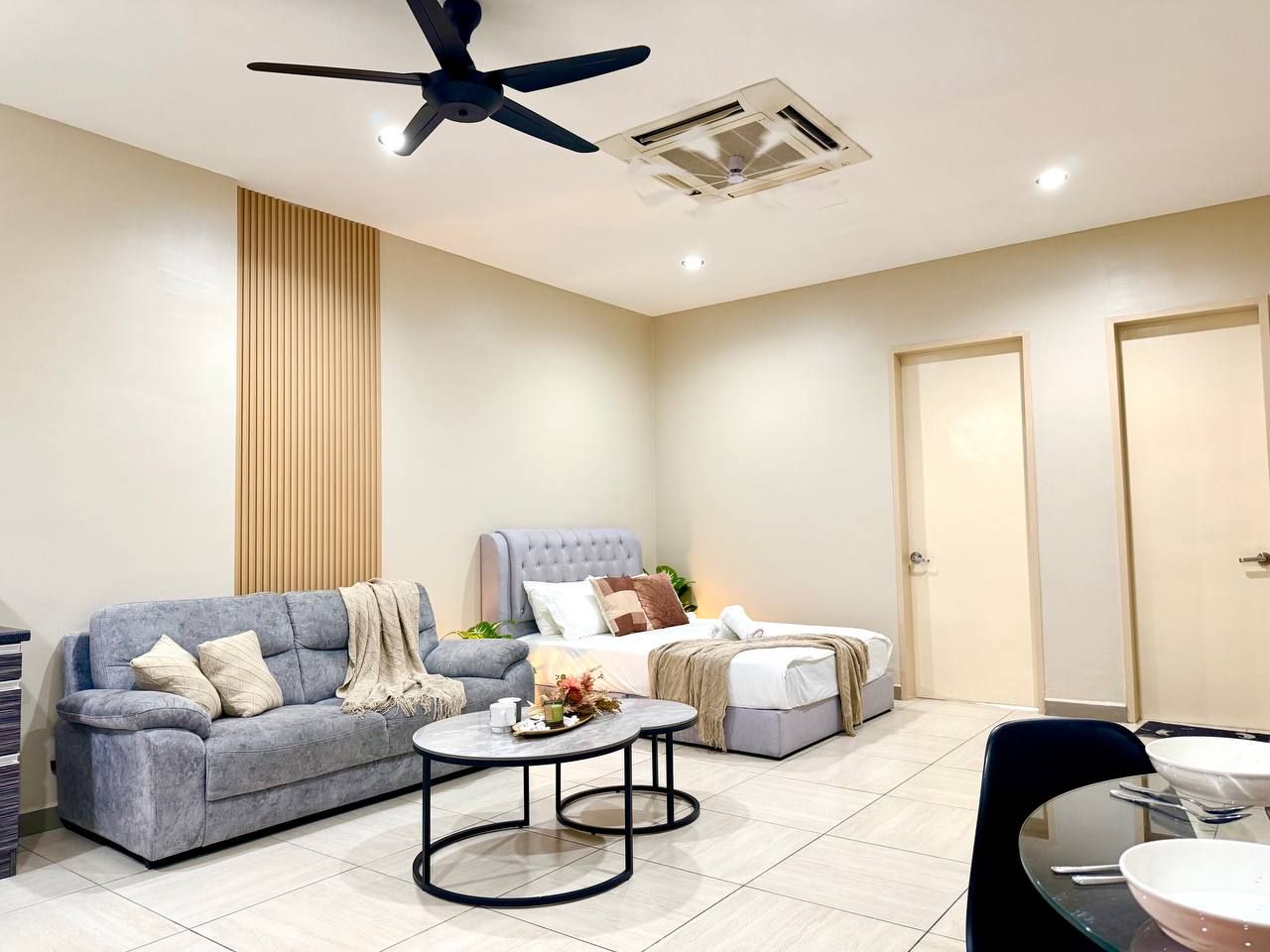 A modern living room with a sofa, a coffee table, a bed, and a dining area.