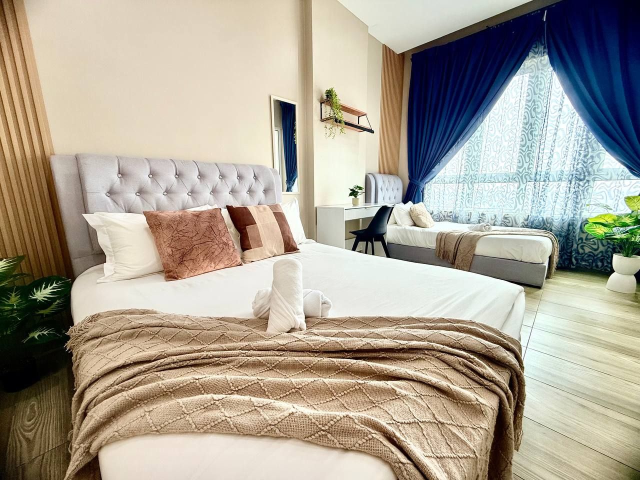 A hotel room with a large bed, a desk, and a window with curtains.
