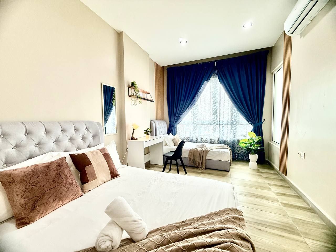A bedroom with a large bed, a desk, and a window with curtains.