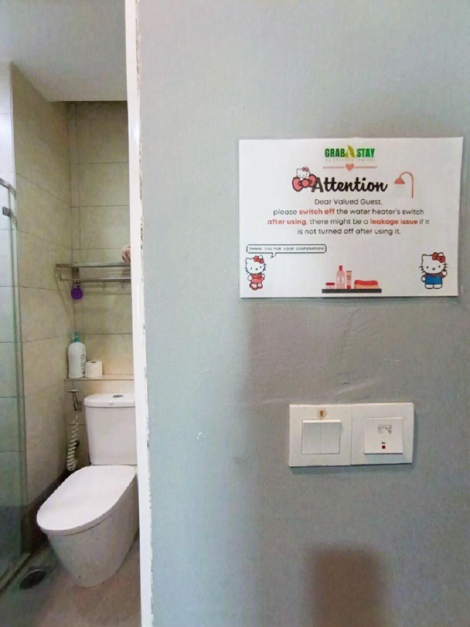 A bathroom with a toilet, a shower, and a wall-mounted sign instructing guests to switch off the water heater's switch after using it.